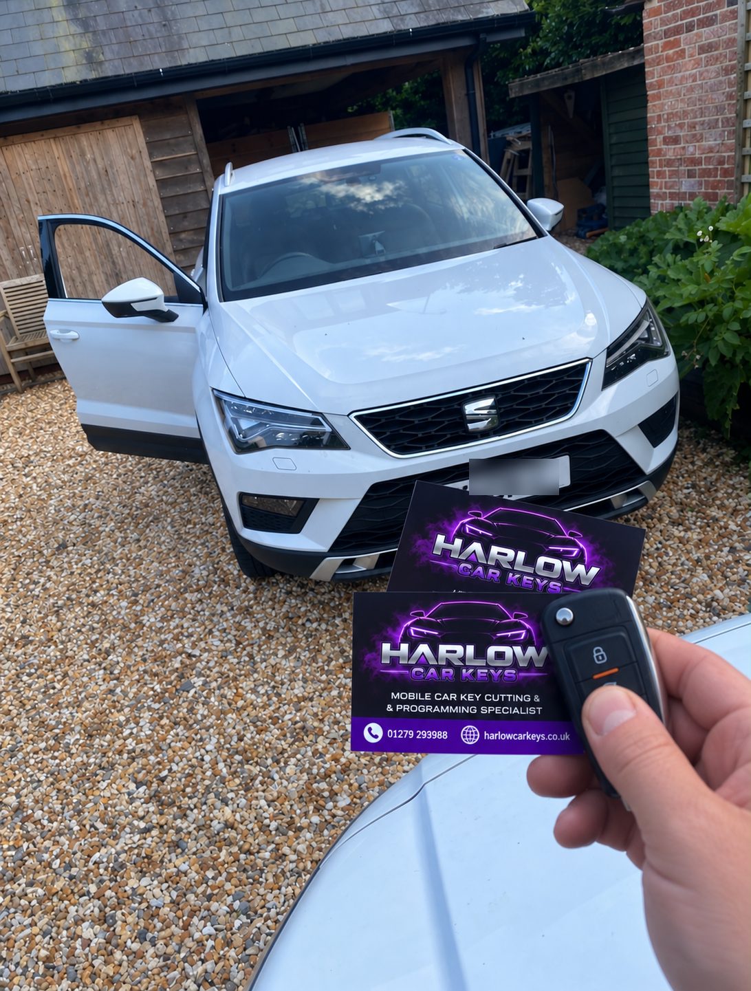 New spare key supplied for a 2018 SEAT Ateca in Sawbridgeworth, held in front of the car with Harlow Car Keys business cards